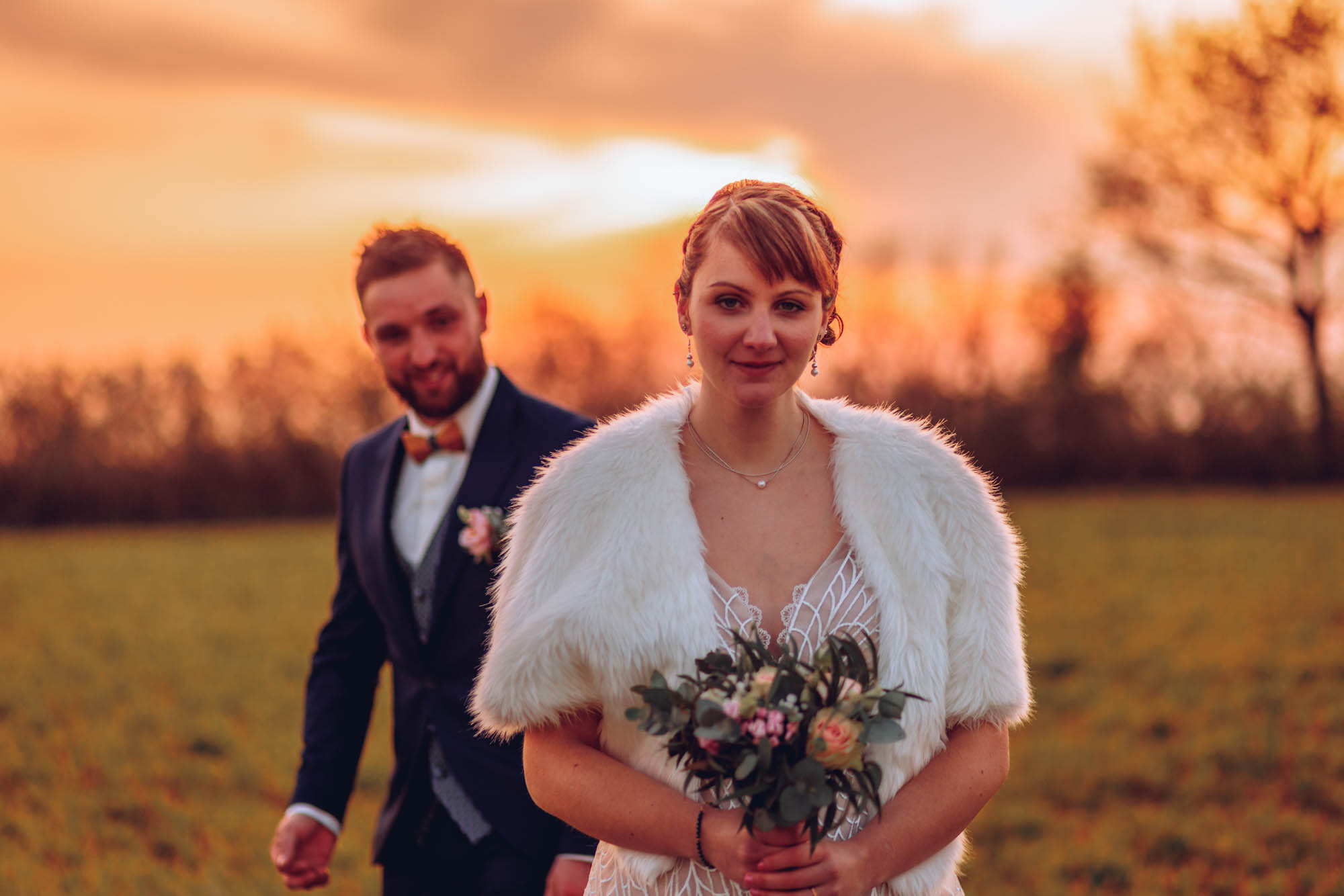 Le marié se tient derrière la mariée au soleil couchant en Vendée
