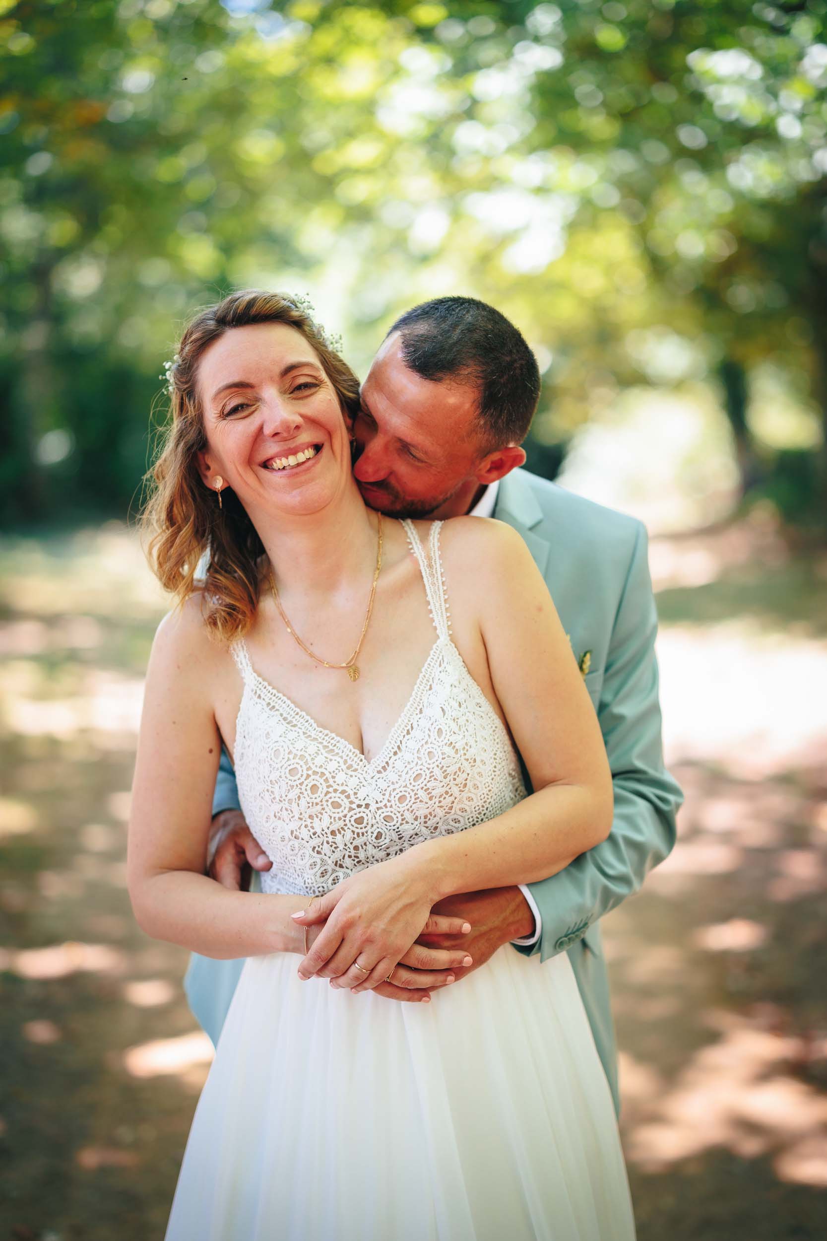 La marié embrasse la mariée dans le cou pour leur photos de mariage aux Herbiers en Vendée