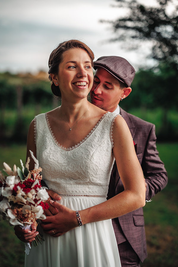 Le marié se tient derrière la mariée pour leurs photos de mariage en Vendée