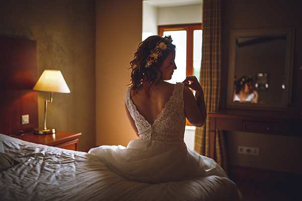 La mariée assise sur un lit pose sa main sur sa robe pour la préparation de mariage à Fontenay en Vendée